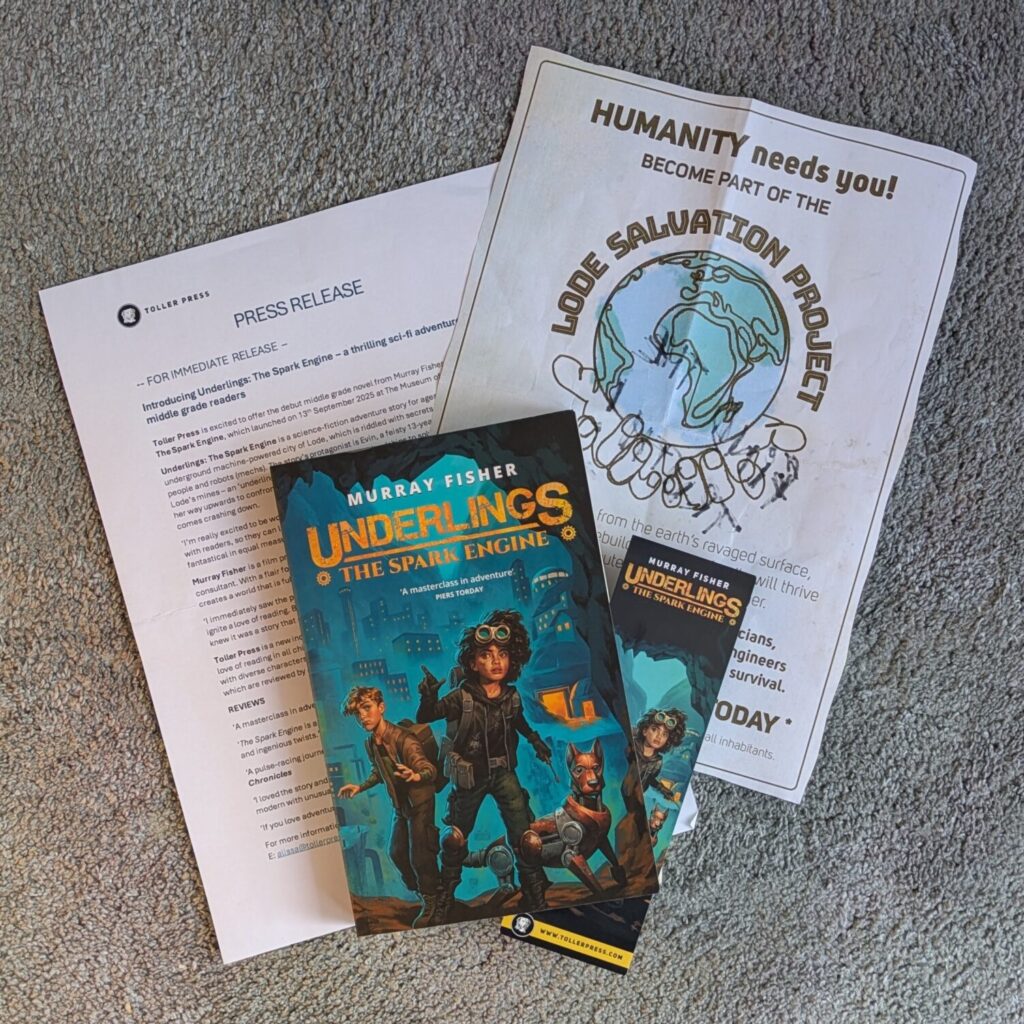 Image shows a copy of the book for review, 'Underlings: The Spark Engine'. Tucked inside is a bookmark of the same design. Below the book is a press release and a poster for the 'Lode Salvation Project'.